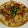 Down Home Shrimp & Grits. Plump shrimp, two types of sausage, ham, onions, mushrooms and red peppers sauteed in our Cajun cream sauce and served over extra cheesy dinner grits! 
